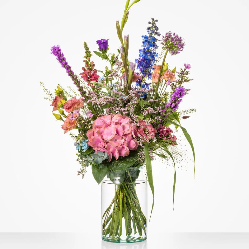 Boeket Zomerweelde in vaas met roze hortensia, blauwe delphinium en zomerse seizoensbloemen