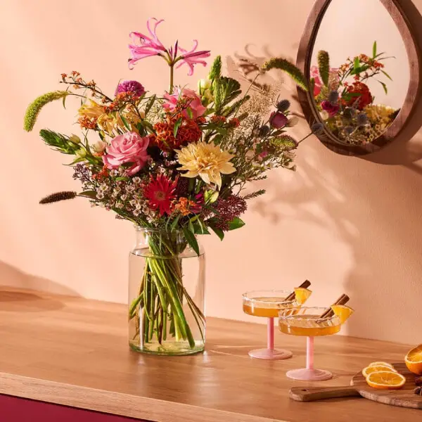 Kleurrijk veldboeket in glazen vaas op houten tafel