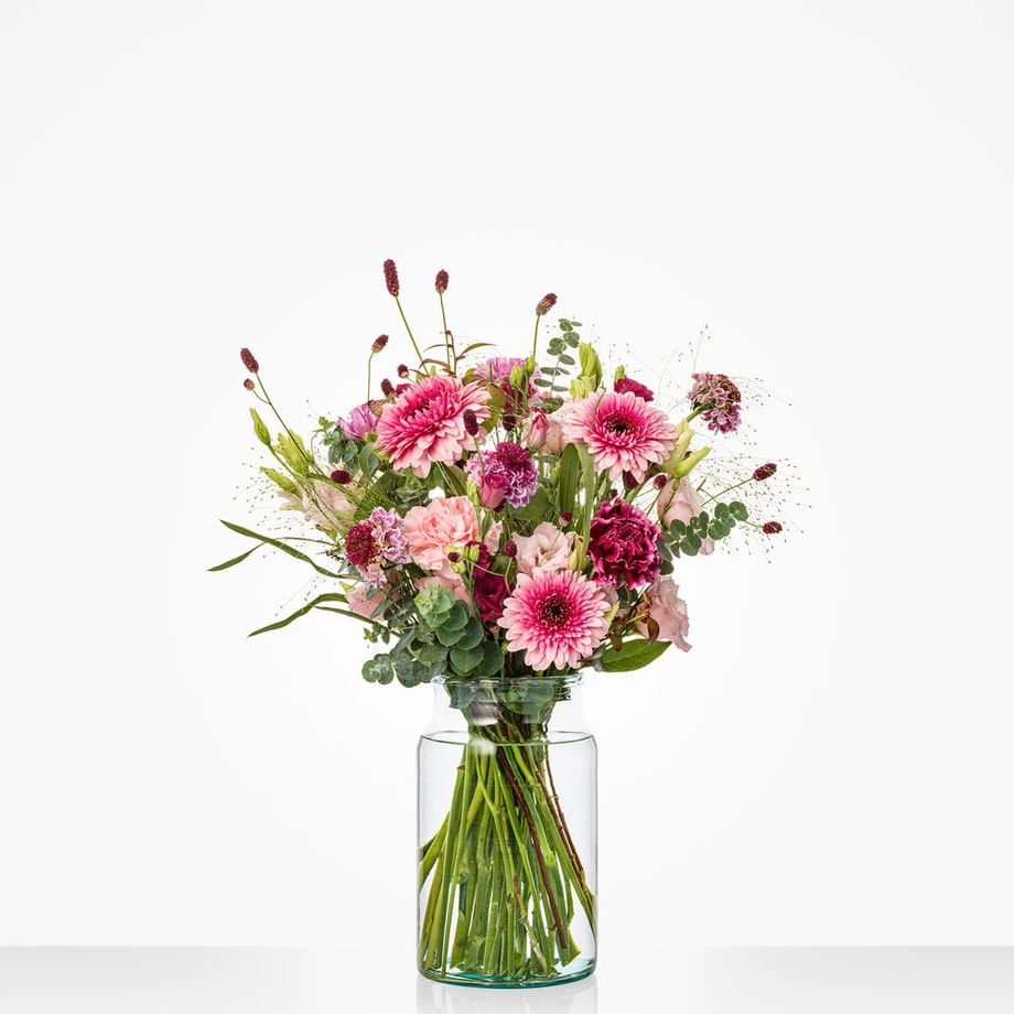 Boeket met roze chrysanten, lisianthus en rode accenten in een glazen vaas