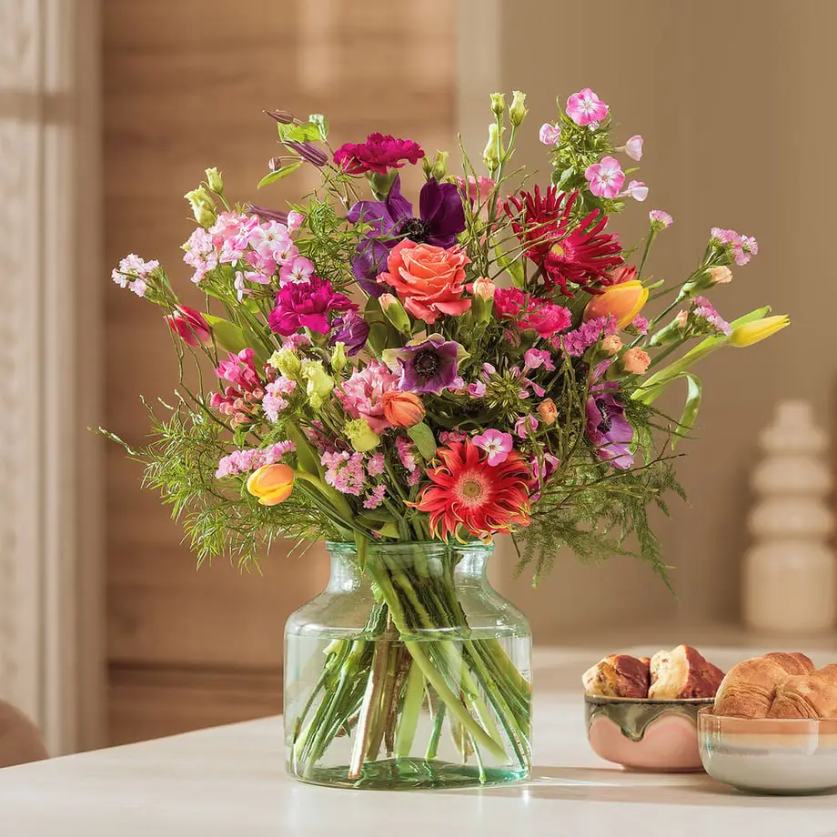 Kleurrijk plukboeket met tulpen, gerbera en rozen op tafel