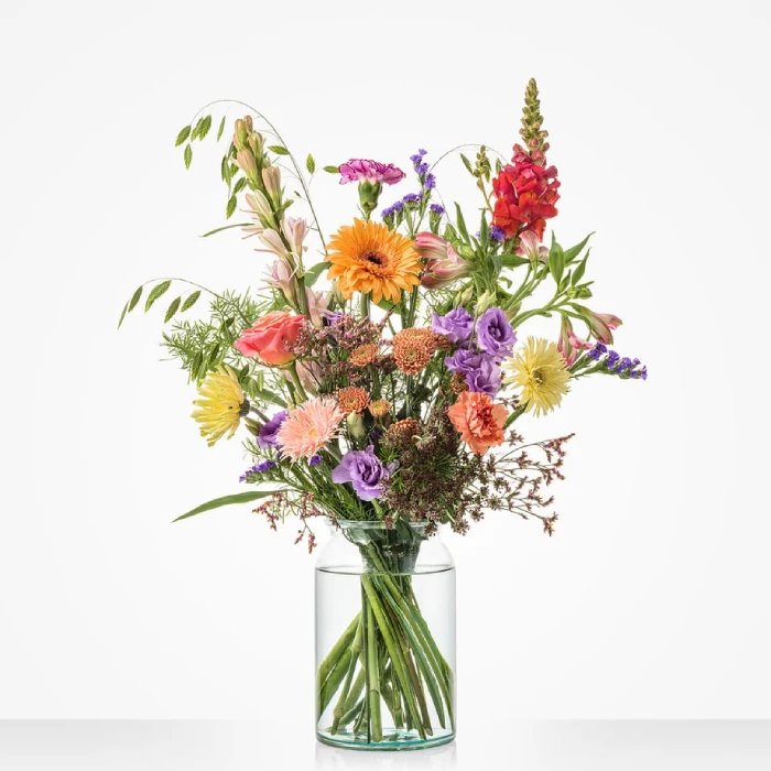 Boeket ‘Gefeliciteerd’ met bloemen in warme, kleurrijke tinten in glazen vaas