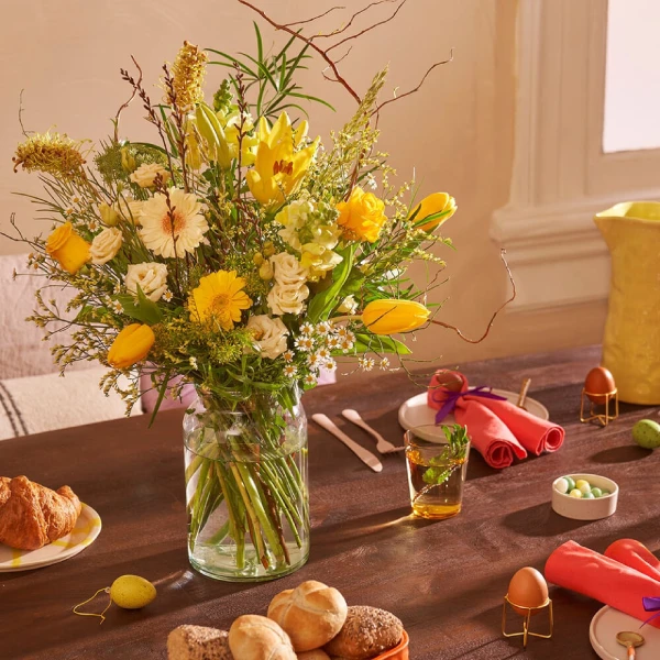 Mooi paasboeket met tulpen, gerbera’s en kamille in gele tinten op de ontbijttafel