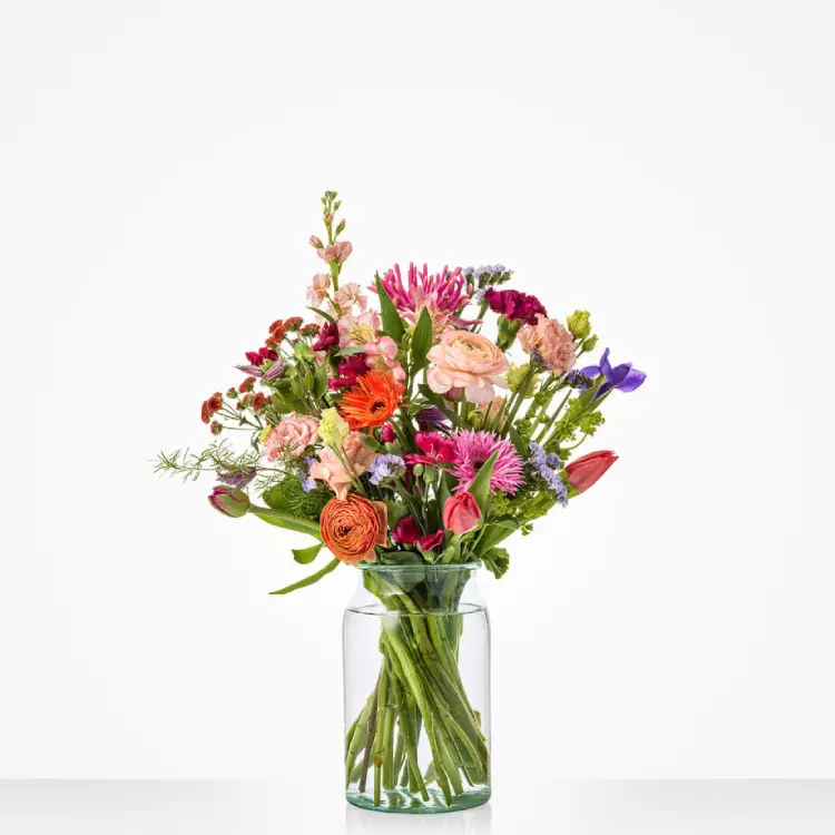 Kleurrijk seizoensboeket met gerbera, ranonkel en tulpen in glazen vaas