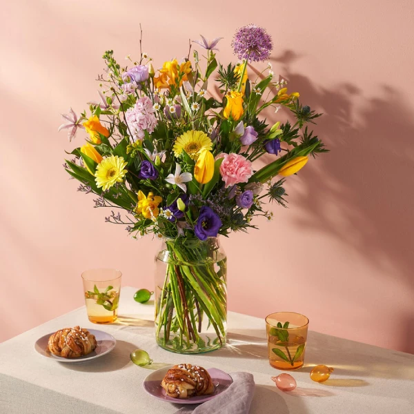 Vrolijk voorjaarsboeket met tulpen, lisianthus en gerbera’s in zachte kleuren op ontbijttafel